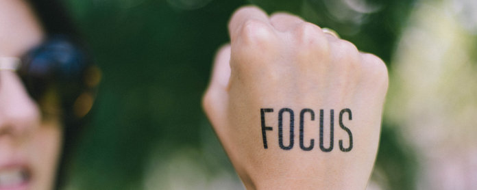 Woman holding fist upright with the word "Focus" on back of the hand