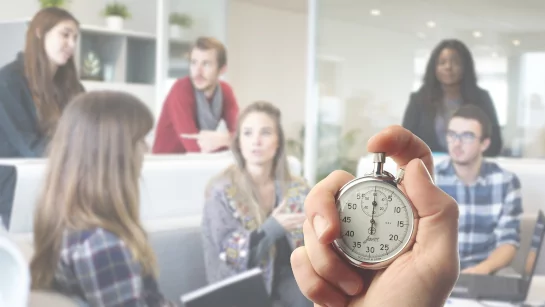 Group of people having business meeting with a hand in focus holding a stop watch